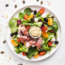 supper in the box ketogenic diet salad with ripening ham, mozzarella, tomatoes, olives, pumpkin seeds and dressing